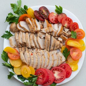 a white plate topped with sliced chicken and tomatoes